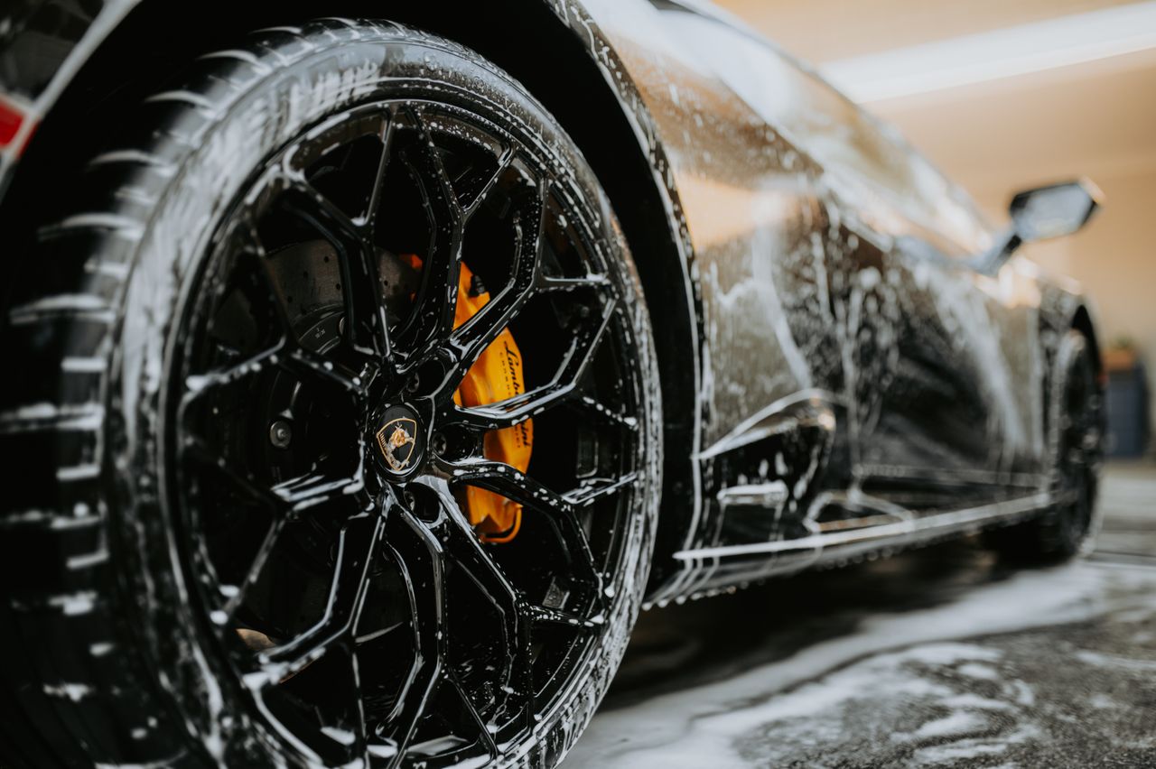 How Successful Entrepreneurs Maximize Productivity Detailed close-up of a luxury car wheel covered in soap suds during a professional car wash.