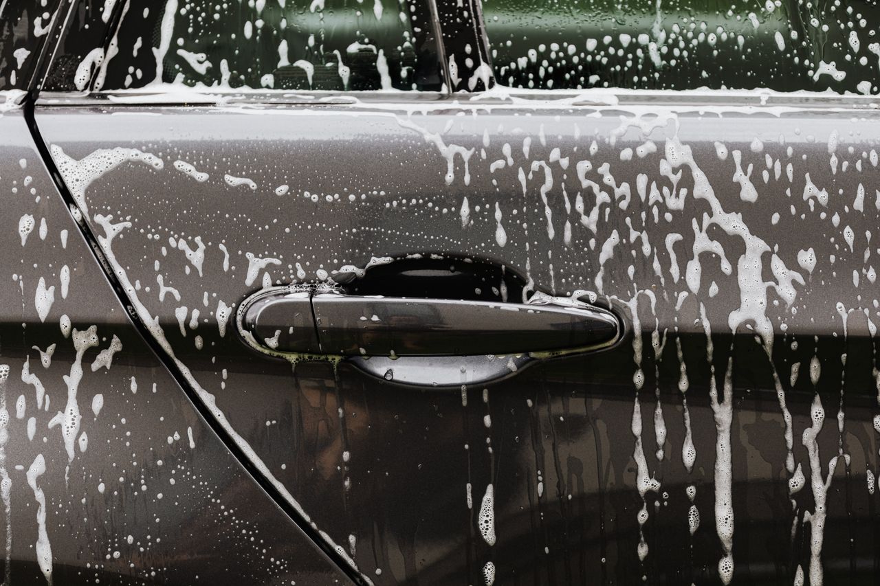The Entrepreneur’s Guide to Turning Ideas Into Profitable Detailed close-up of soap suds on a black car door during a wash, highlighting automotive care.